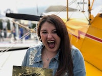 a woman holding a book in front of a yellow airplane
